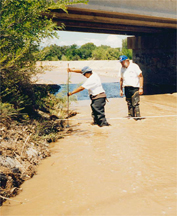 Collection of suspended sediment sample after storm event on the Pajoaque River at El Rancho, New Mexico; Naomi Archuleta, Pueblo of San Ildefonso (left), and Robert McBreen USGS (right).  Photographer: Cyndie Abeyta.